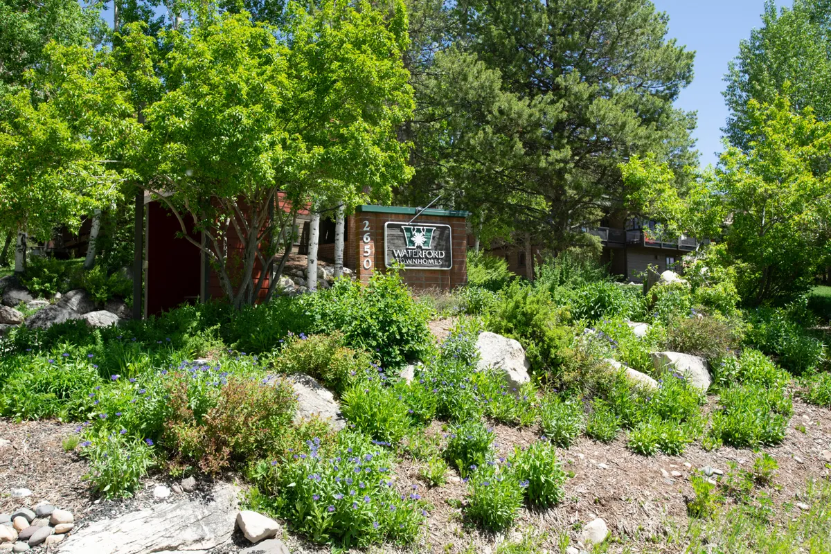 This exterior image displays the entrance signage for Waterford Condominiums set amidst lush greenery and rocky landscaping. It conveys a peaceful, welcoming atmosphere in a well-maintained natural setting that hints at the nearby trails and open outdoor spaces.