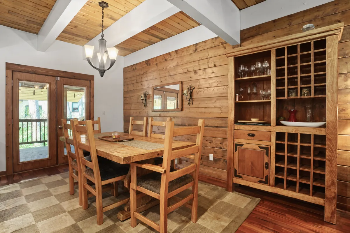 A spacious dining area featuring a sturdy wooden table surrounded by matching chairs, with large windows letting in plenty of natural light. The sideboard and cozy decor create an inviting atmosphere for group meals, game nights, or celebrations.