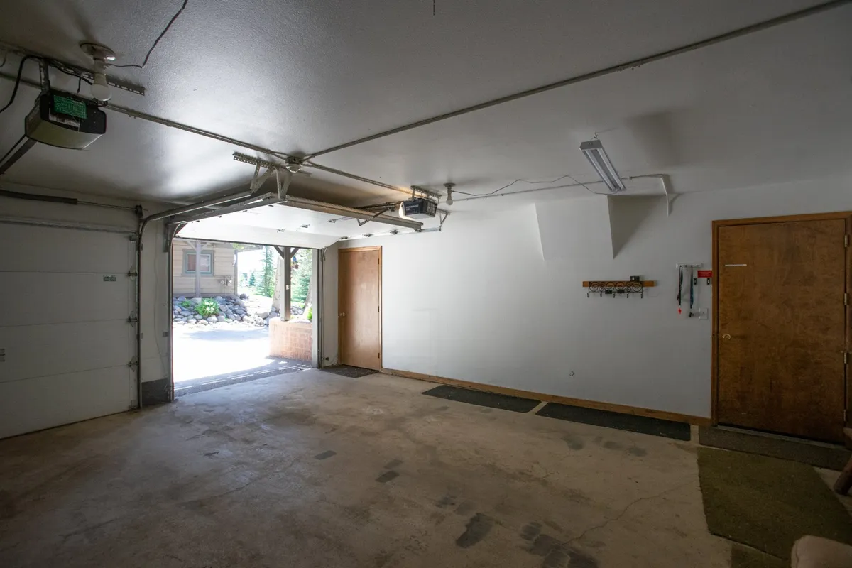 A functional garage or utility entry area with a visible garage door, entrance door, and durable flooring. The space is uncluttered and practical, suggesting ample room for storing outdoor equipment and easy transitions between indoor and outdoor activities.